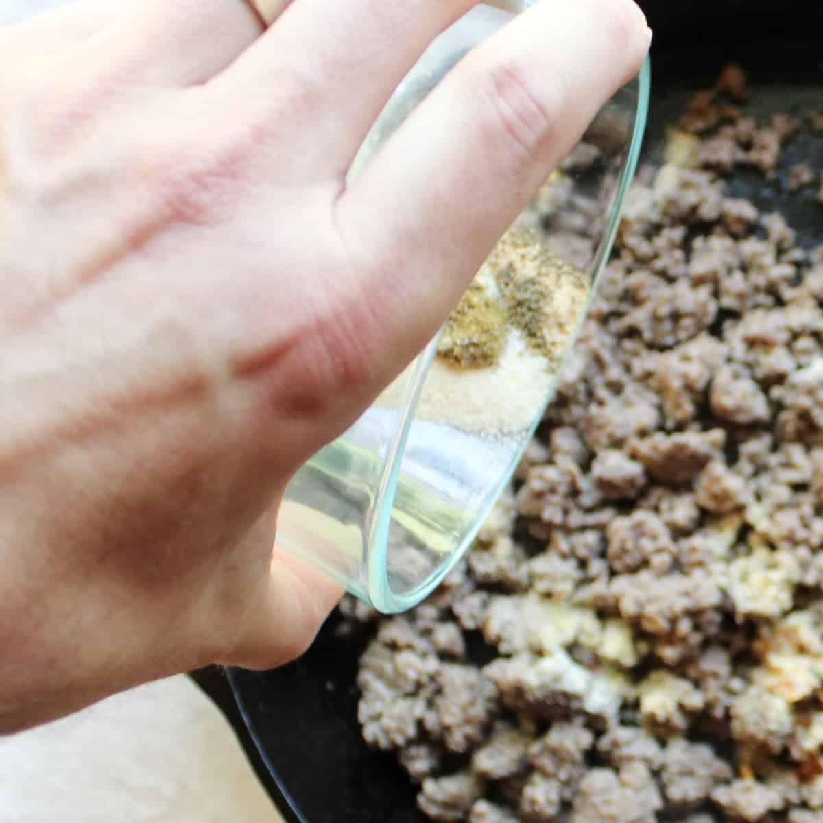 adding seasoning blend to cooked ground beef