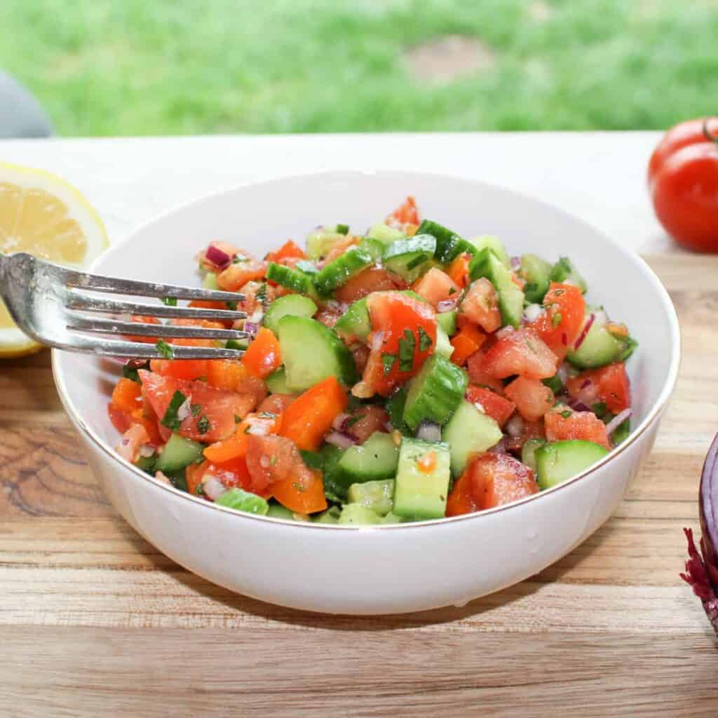 mediterranean cucumber tomato salad in a bowl with a fork with a nice background