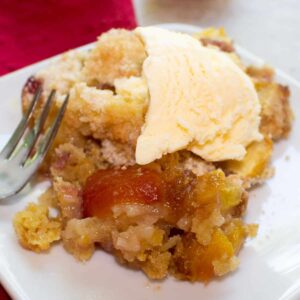 scoop of peach crumble on a plate with ice cream