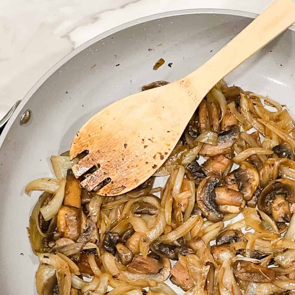 sauteed button mushrooms in a pan with a spoon